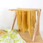 DIY pasta drying rack with homemade fettuccini noodles drying on the dowels.