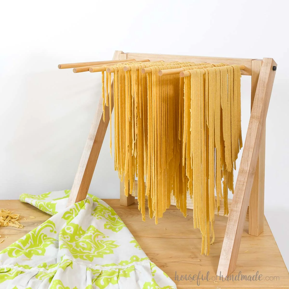 DIY pasta drying rack with homemade fettuccini noodles drying on the dowels.