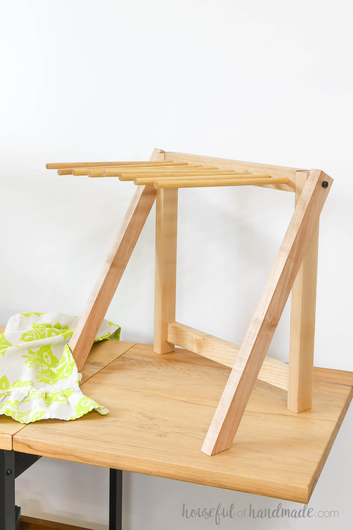 Empty hardwood pasta rack on table next to decorative towel. 