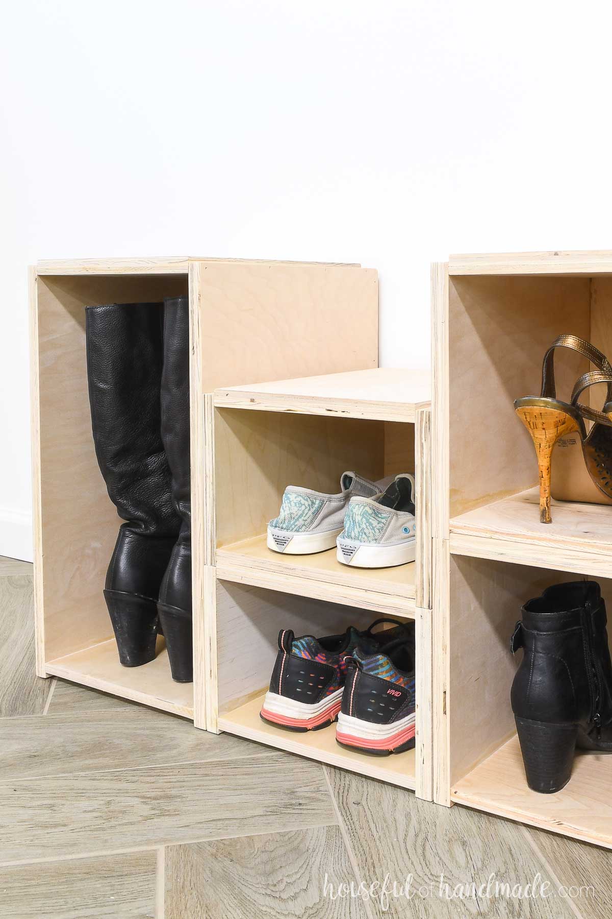 Tall shoe box with boots, small shoe boxes with sneakers, and medium shoe boxes with ankle boots and heels in them. 