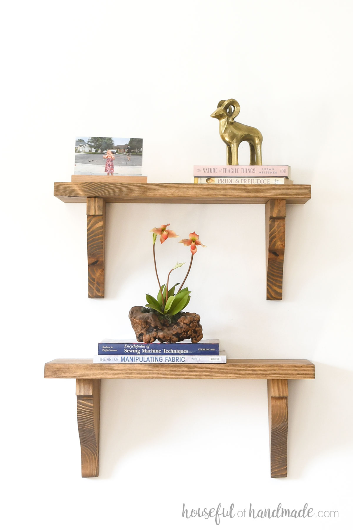 Two shelves with wood shelf brackets holding books and nicknacks. 