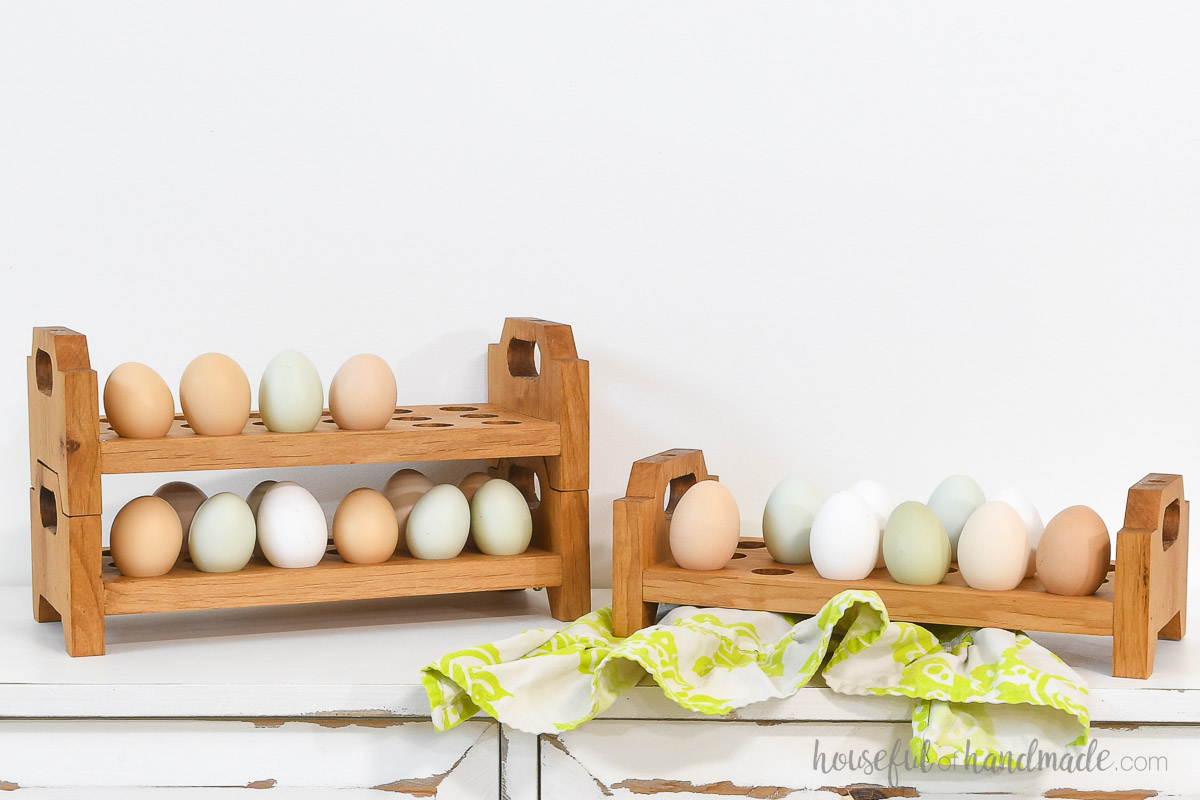 Two egg trays stacked together with colorful eggs on them and a third tray on the side. 