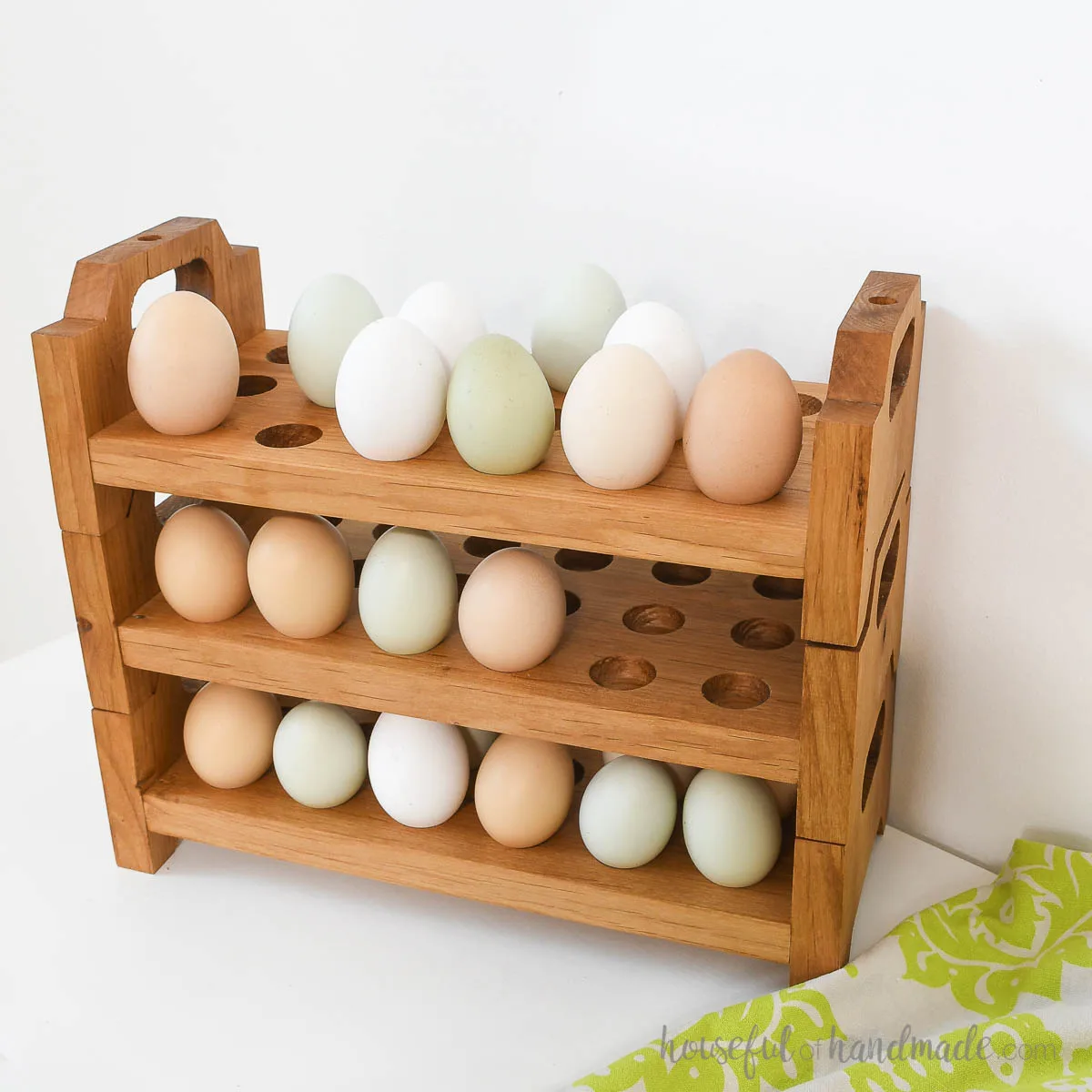 Three alder egg trays holding farm eggs in a variety of colors stacked together.