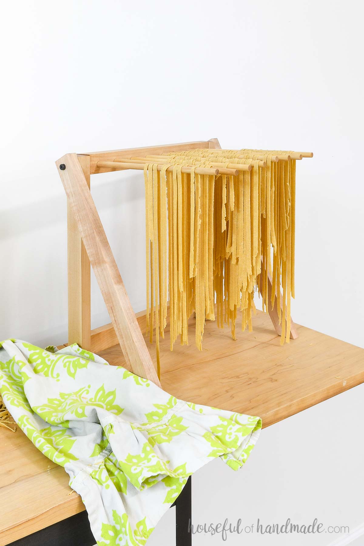 Folding rack with dowels drying homemade pasta on it. 