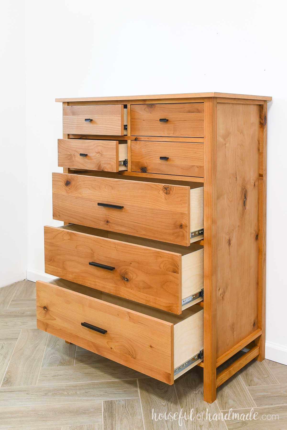 Warm wood dresser with 7 drawers slightly open to show the sides. 