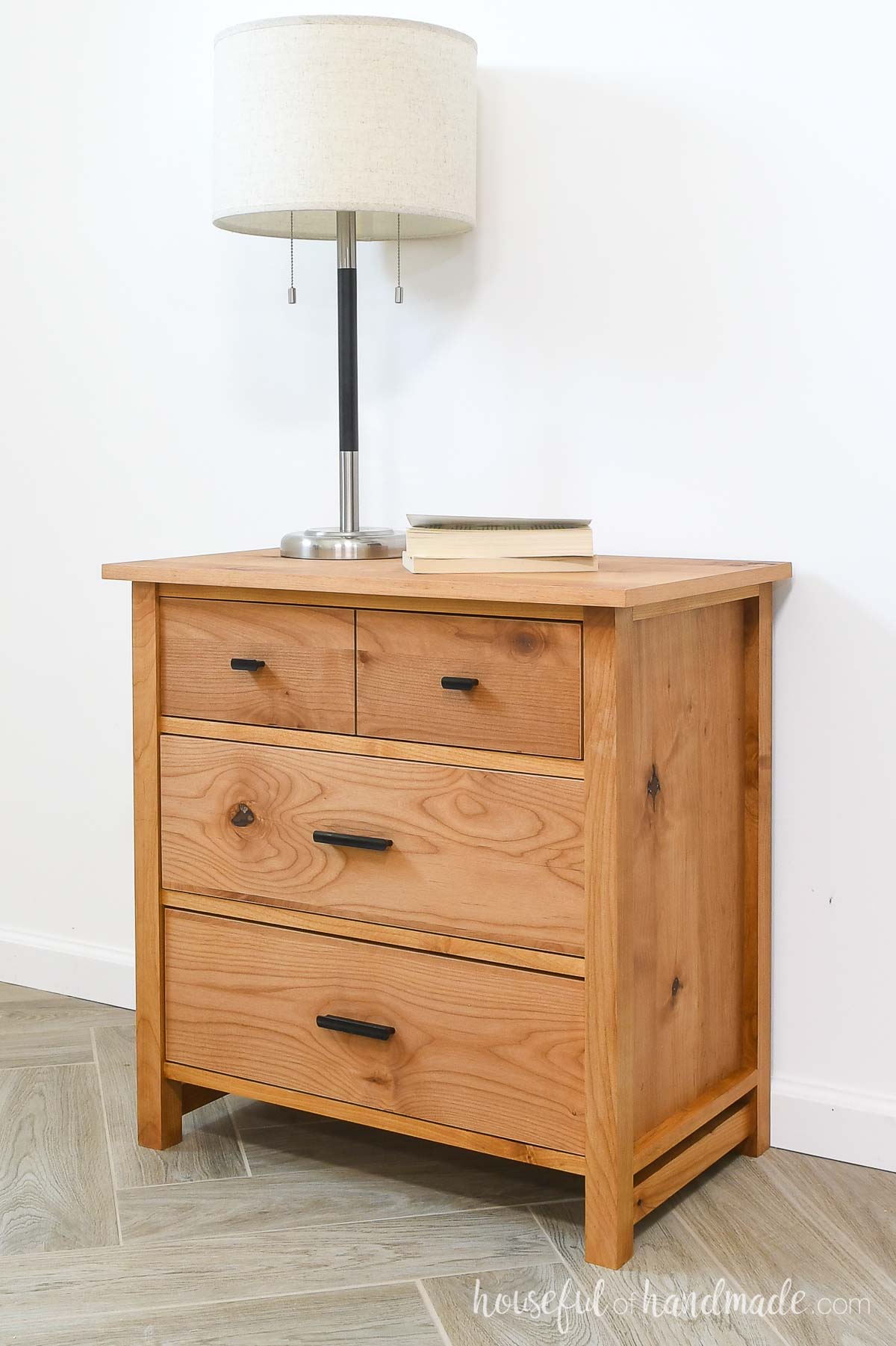 Simple nightstand with 3 drawers, the top one looks like 2 small drawers, made from warm colored wood. 