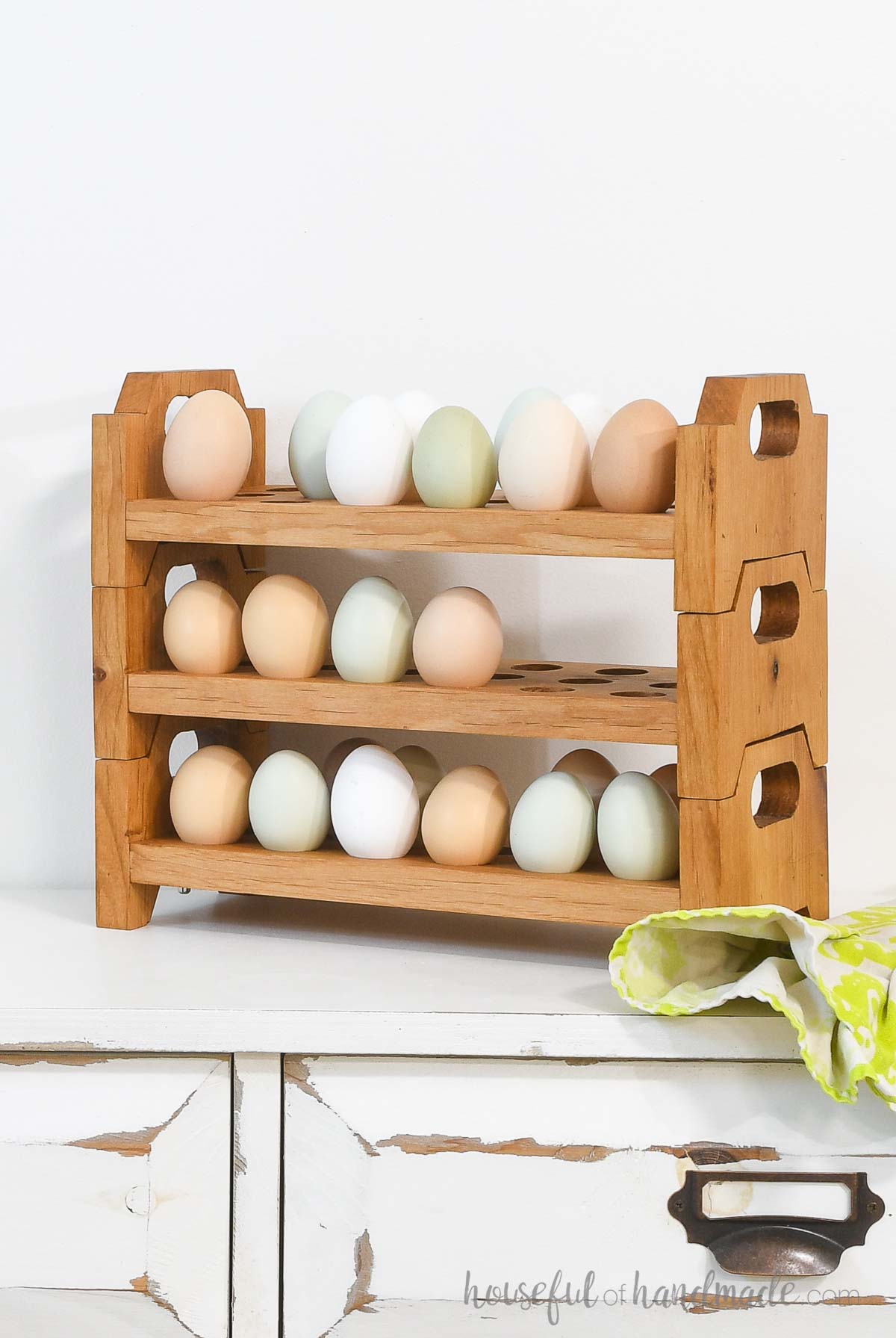 White, brown, cream, blue and green farm eggs in three wood trays stacked on top of each other.