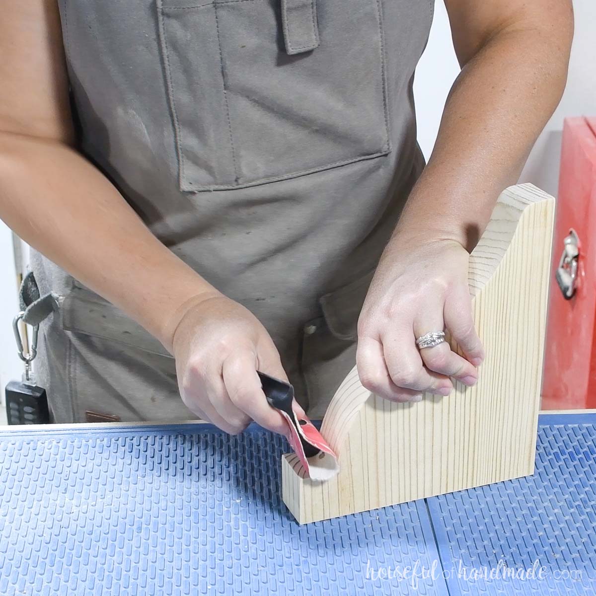 Sanding a wood shelf bracket by hand. 