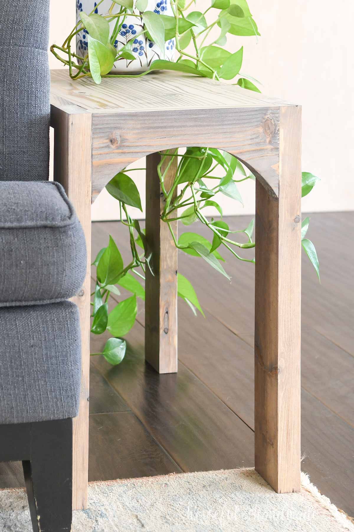 Simple side table with chunky legs and flat top and arch in between front legs. 