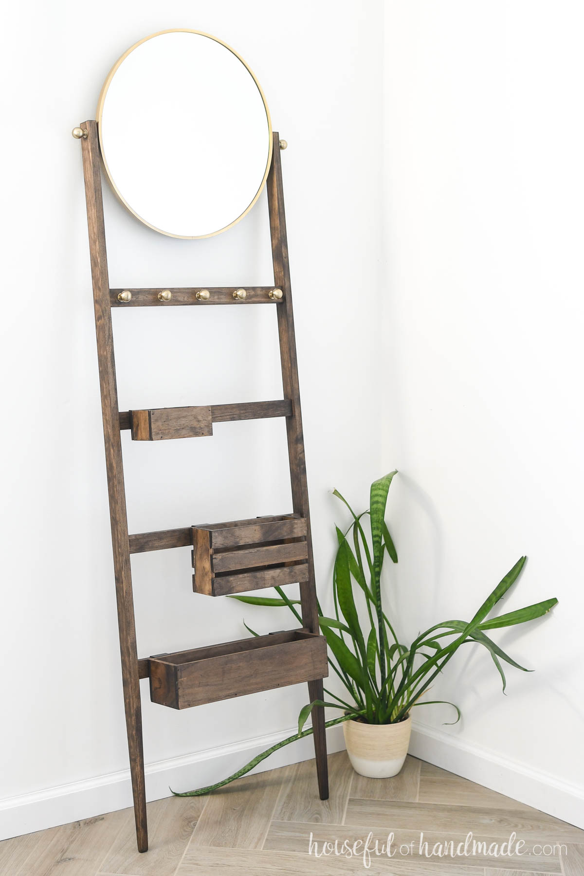 Ladder with bins for storage and a mirror on top leaning against the wall.