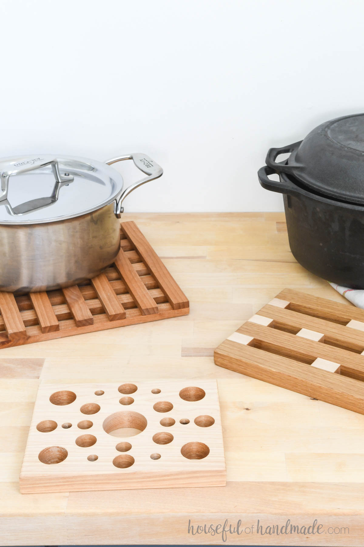 Three different styles of wood trivets on a butcher block countertop. 