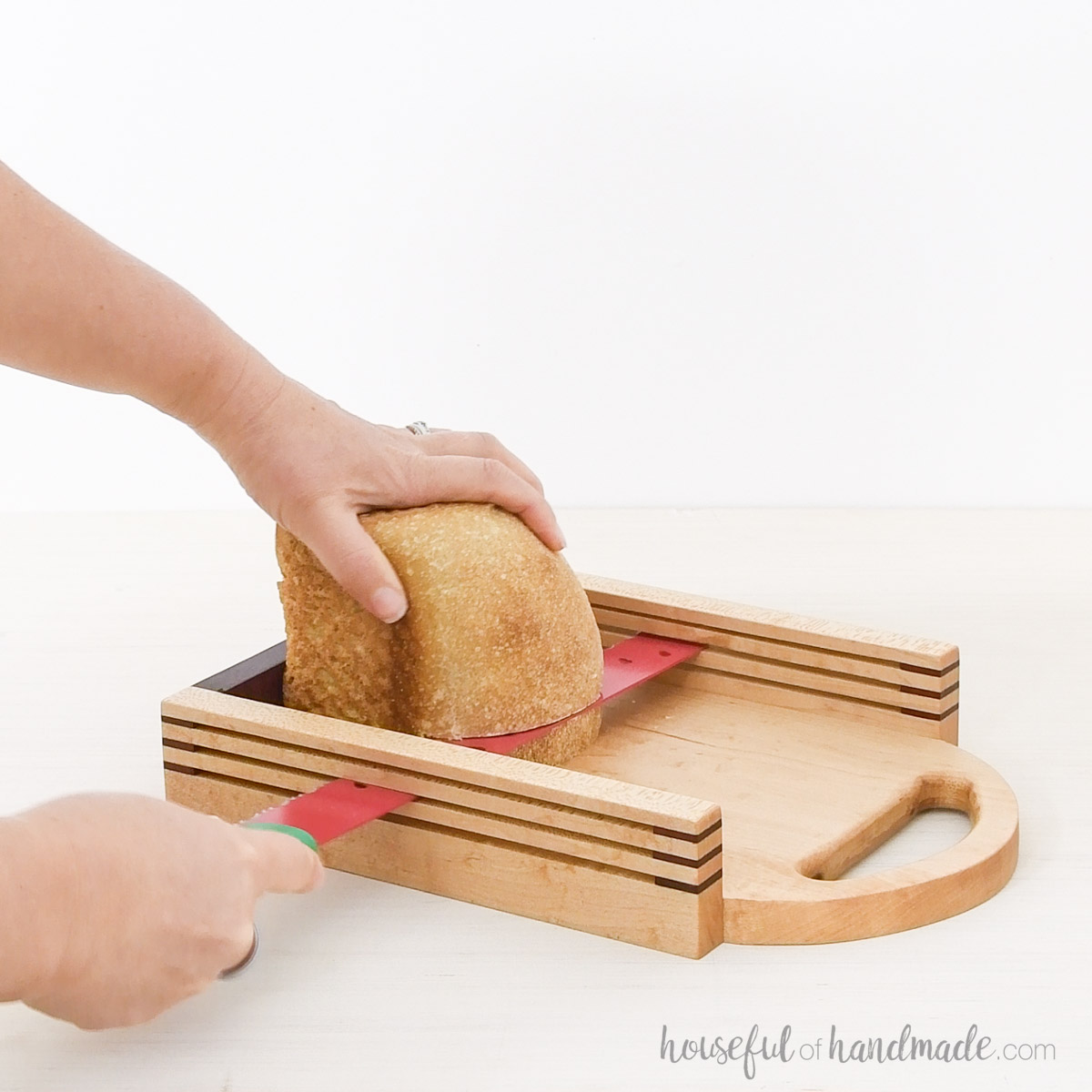 Slicing a loaf of sourdough bread in a wood bread slicer.