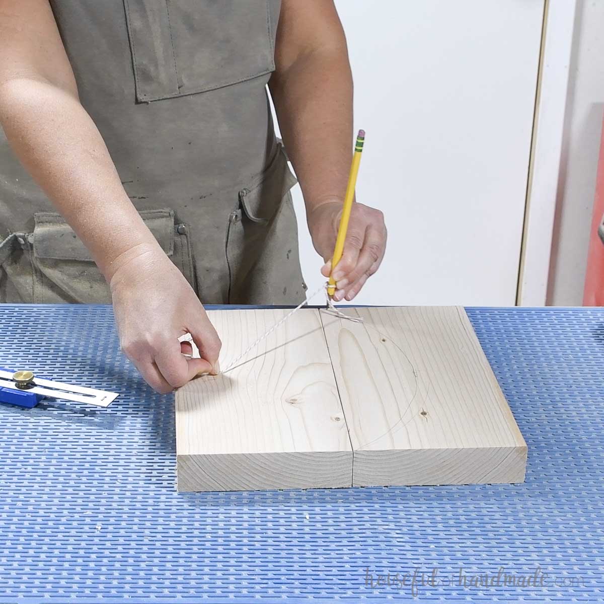 Drawing an arch on a board with a pencil and string.