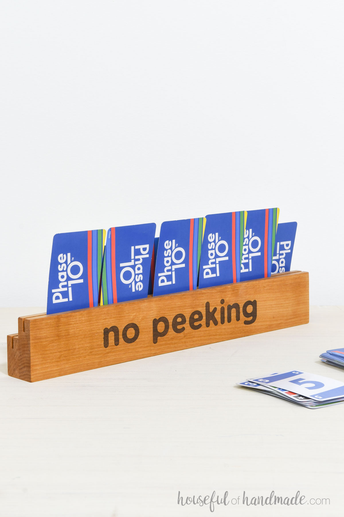 "No Peeking" stained on the back of a wood card holder with playing cards inside it. 