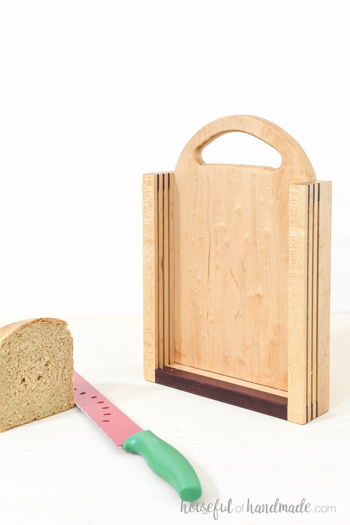 Wooden bread slicers with 3 thickness guides sitting next to a loaf of bread. 