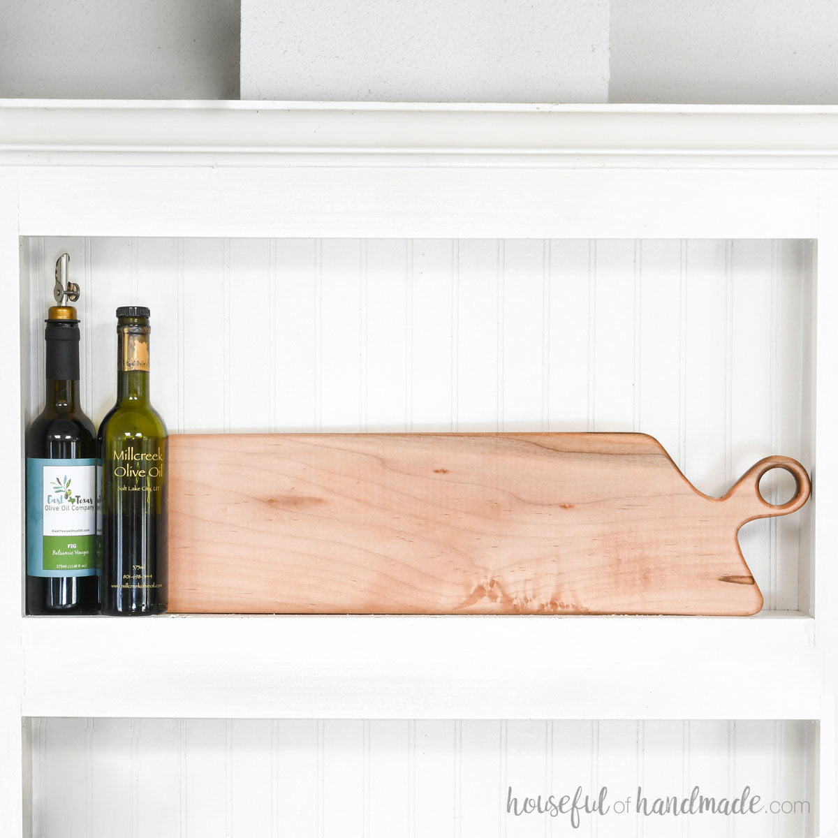 DIY long maple breadboard in a cubby with beadboard behind it and oils next to it. 