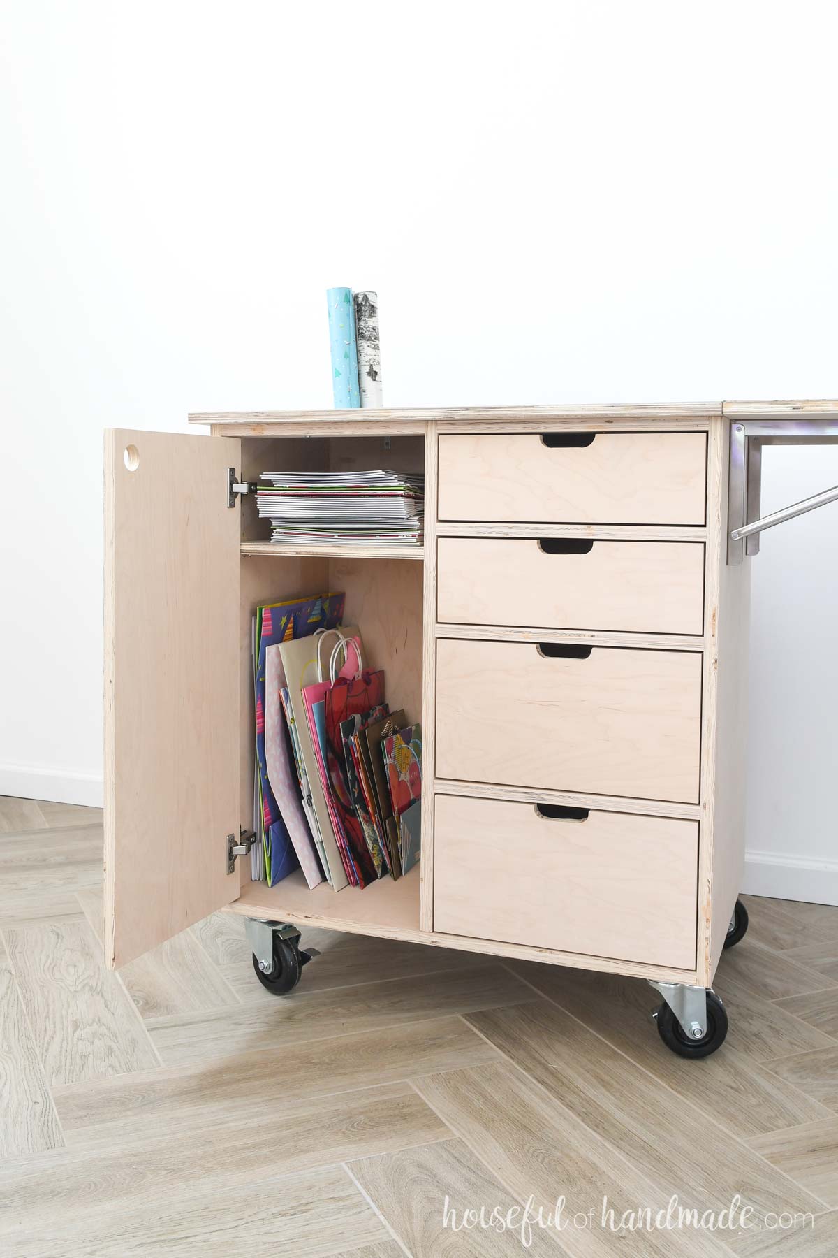 Wrapping paper storage cart with cabinet for gift bags and boxes and drawers. 