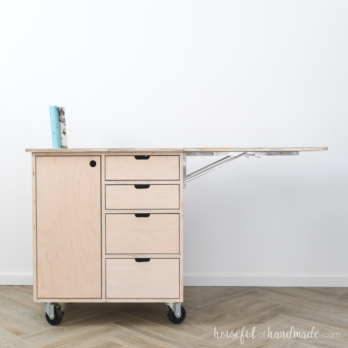 DIY gift wrapping cart with 4 drawers and a cabinet and a leaf on one side.