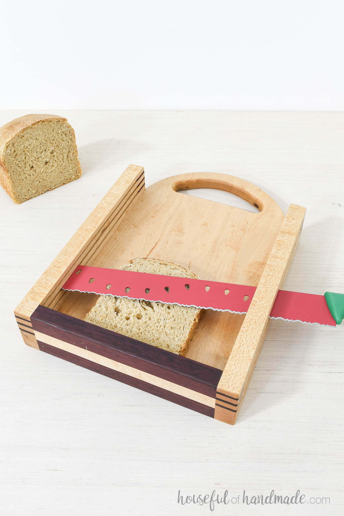 DIY bread slicer with slice of bread in it and bread knife in the cutting grooves. 