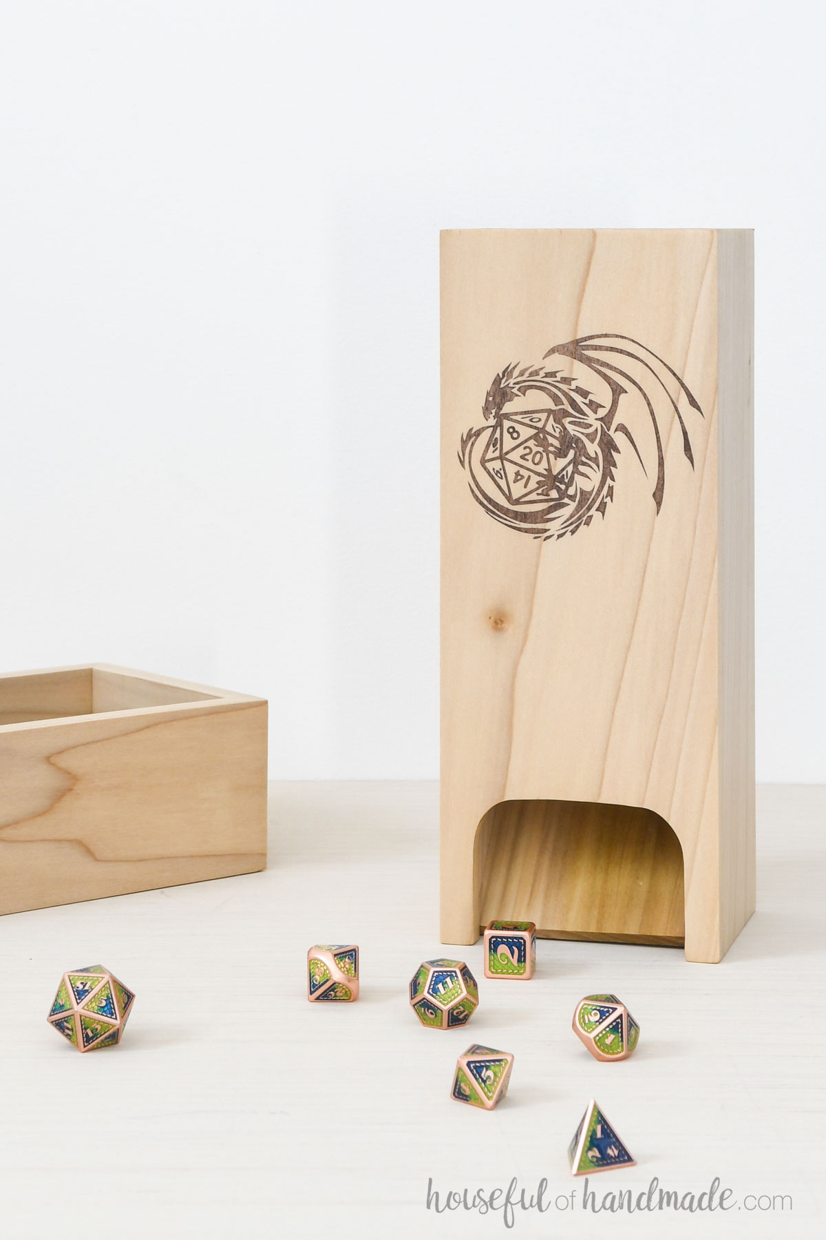 Wood dice tumbler with dragon and dice design on the front next to a matching tray and dice around it. 