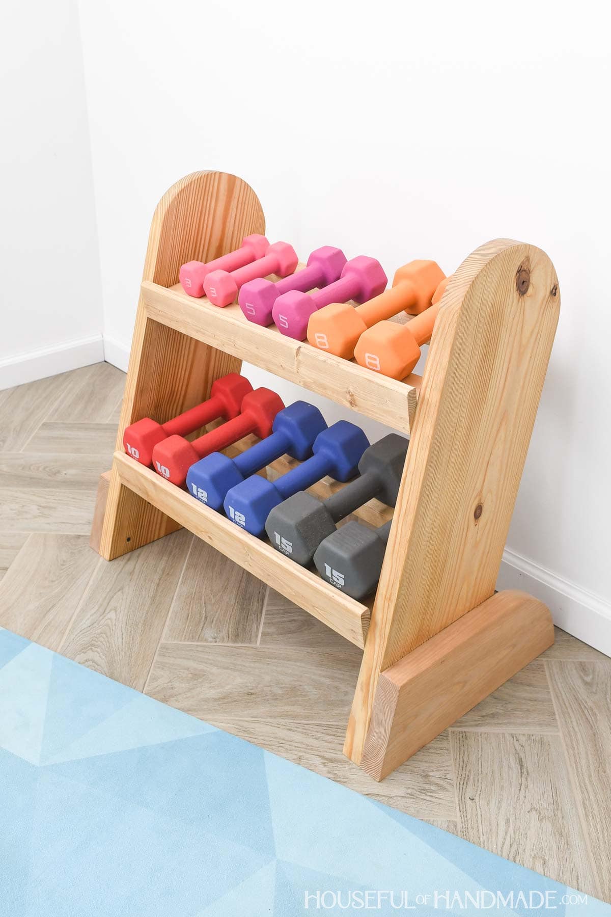 Weight rack with 6 sets of dumbbells on it made from wood. 