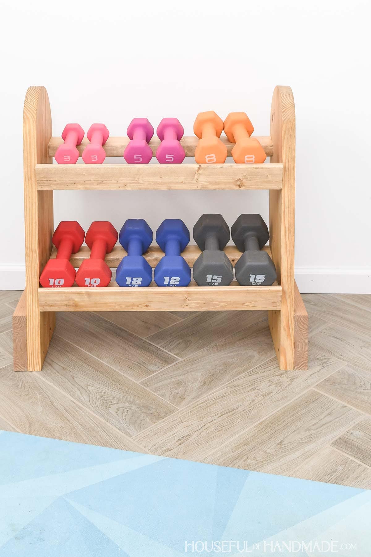 Six weights on a DIY wood dumbbell rack.