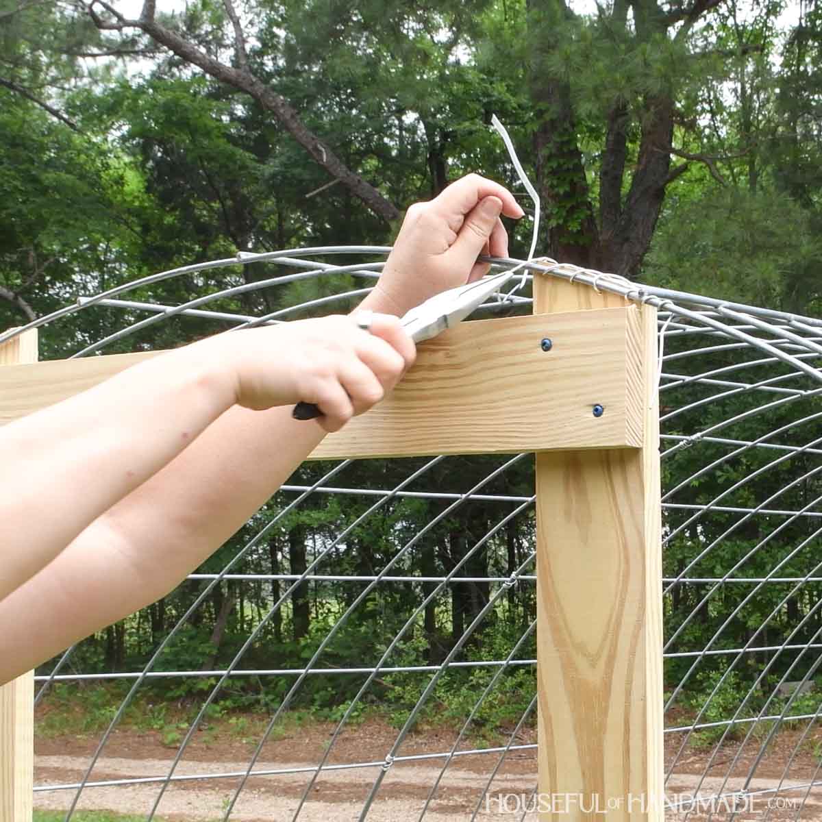 Attaching the top of the door frame by sewing wire through the holes and attaching it to the wire hoop.