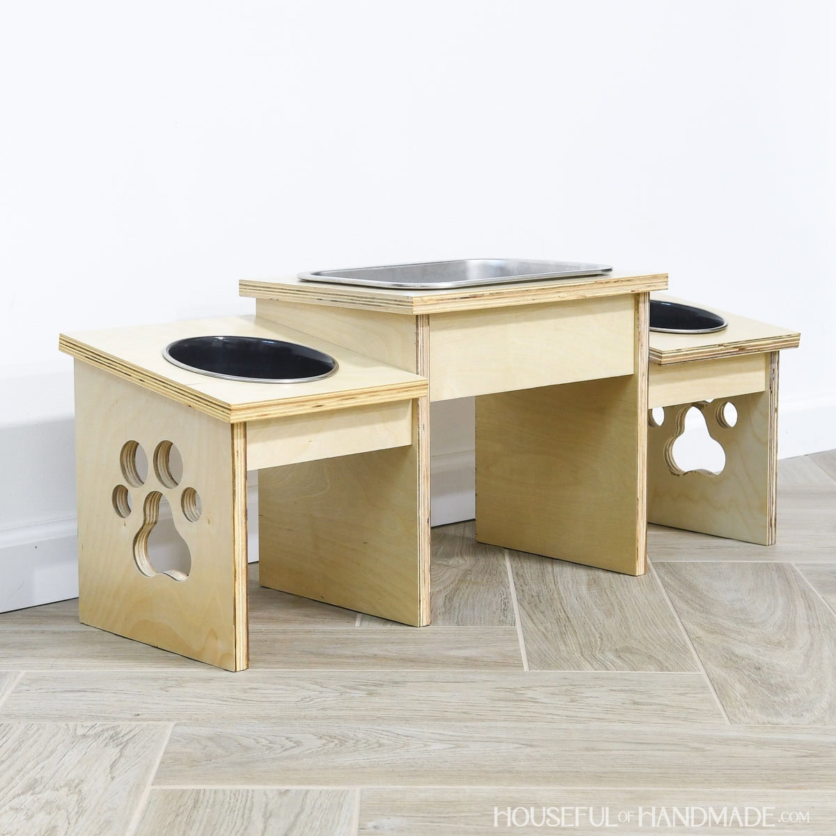 DIY dog bowl stand made from plywood scraps with a paw cut out in the sides.