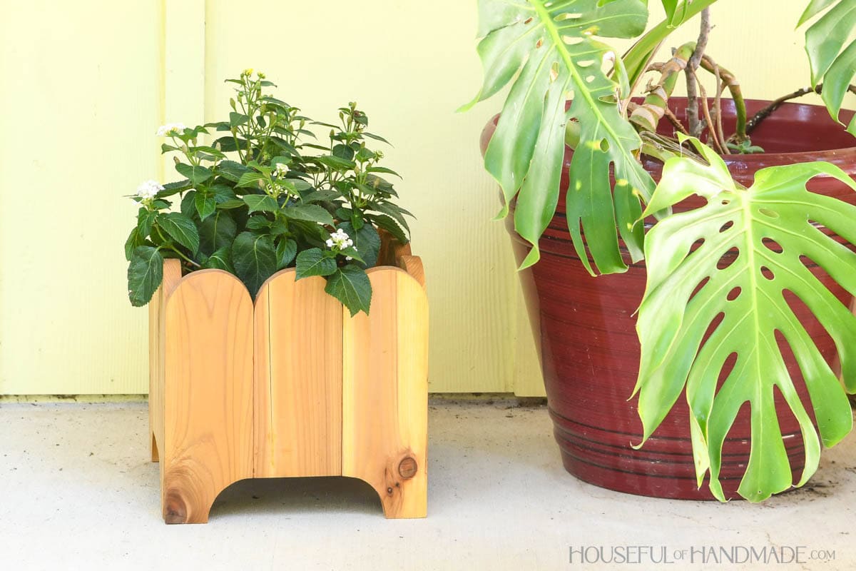 DIY wood planter box with plant inside on a porch. 
