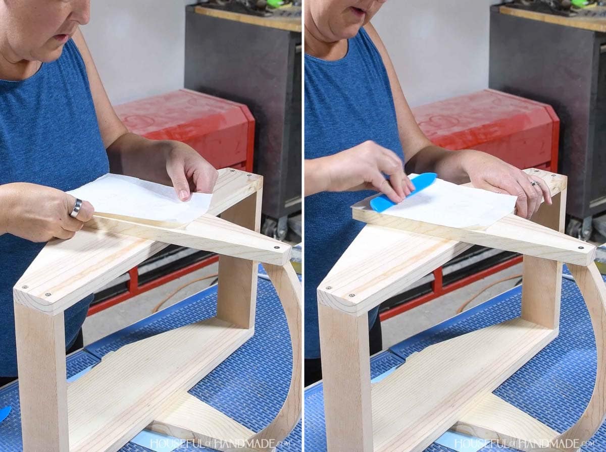 Rubbing a vinyl stencil on the piece of wood.