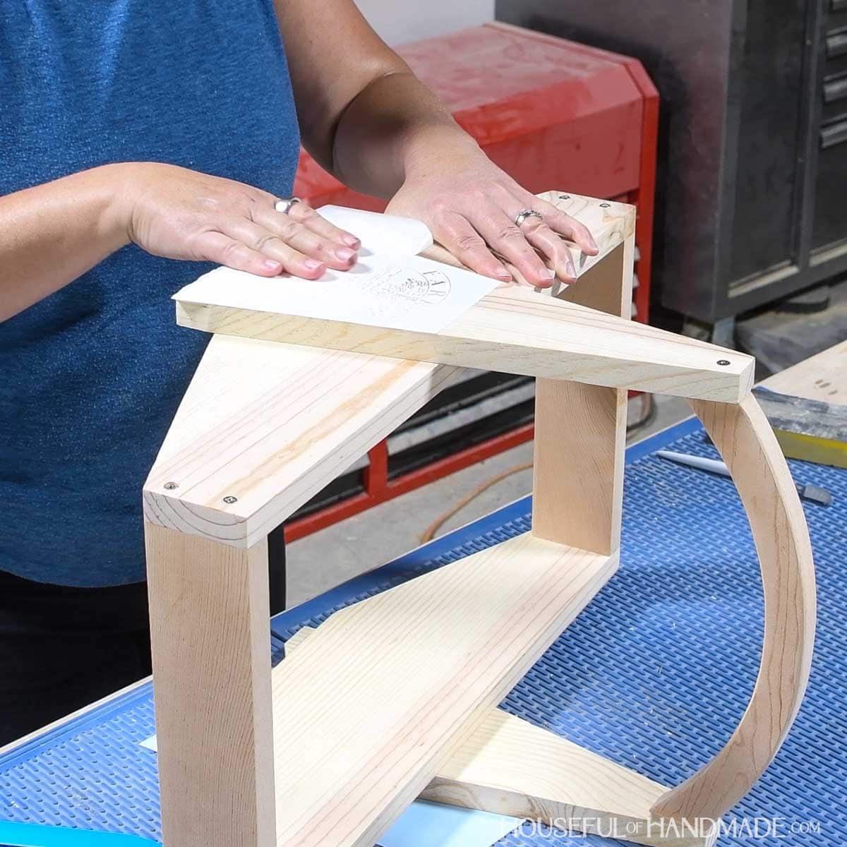 Pealing back the transfer paper on a stencil on wood. 