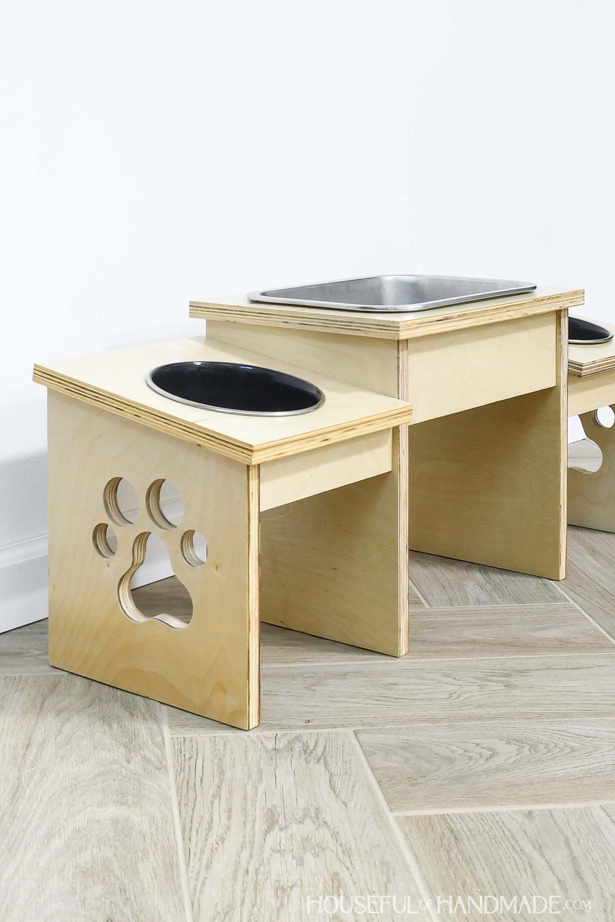 Angled wood dog bowl holder with paw print cut out.