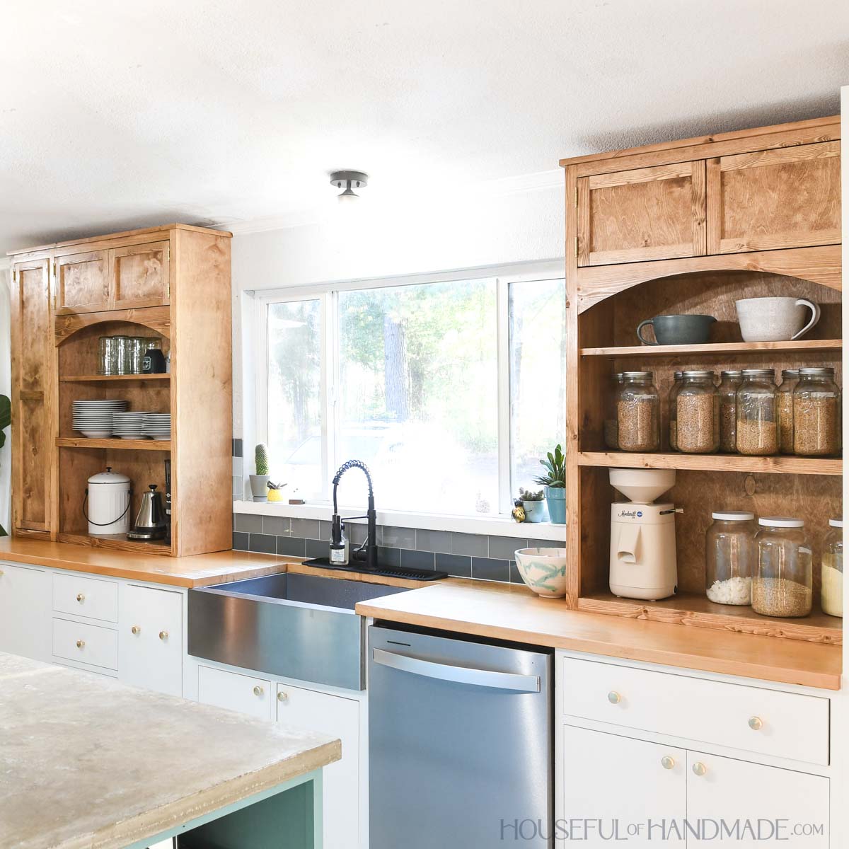 Kitchen wall with two countertop kitchen cabinets with arches on them and sink in the middle.