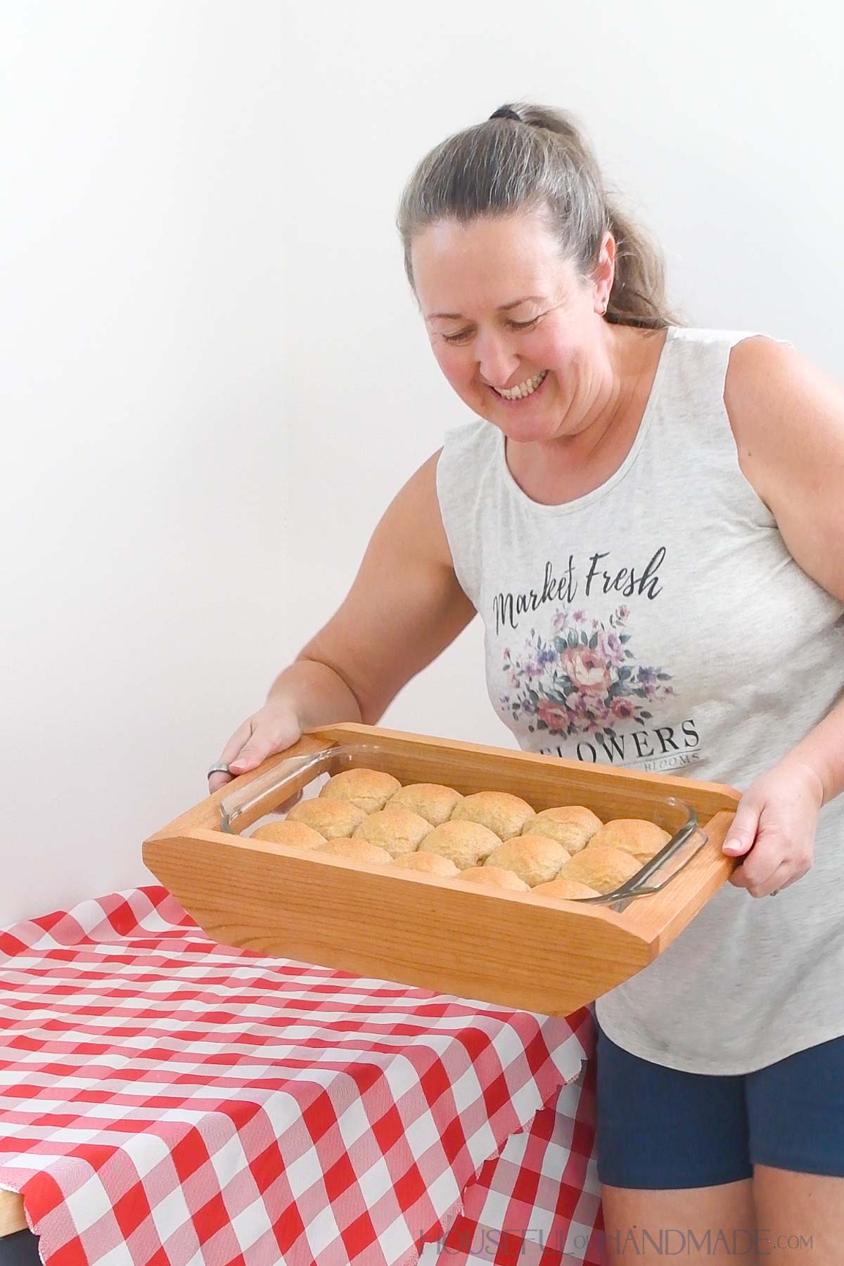 Kati carrying a 9x13 baking dish of hot rolls in a wooden carrier.