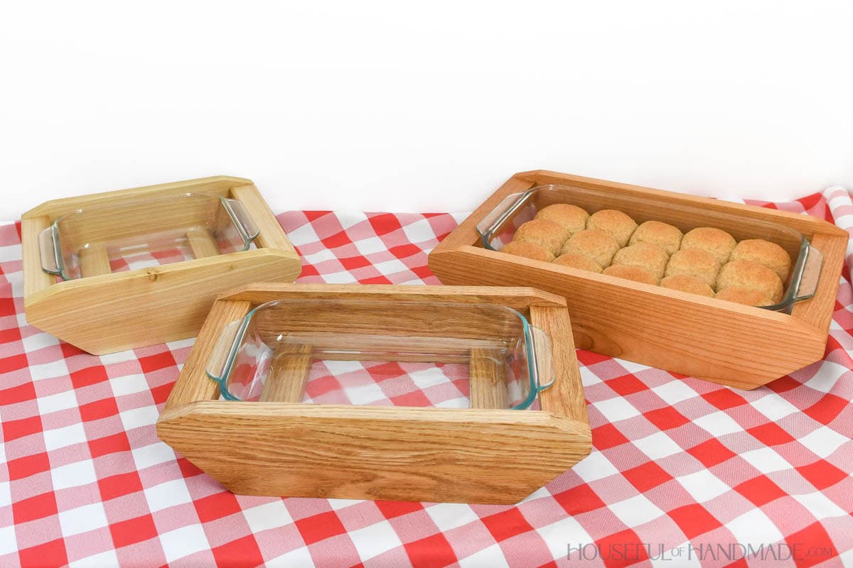 Three wooden baking dish carriers in different sizes with Pyrex bakeware inside.