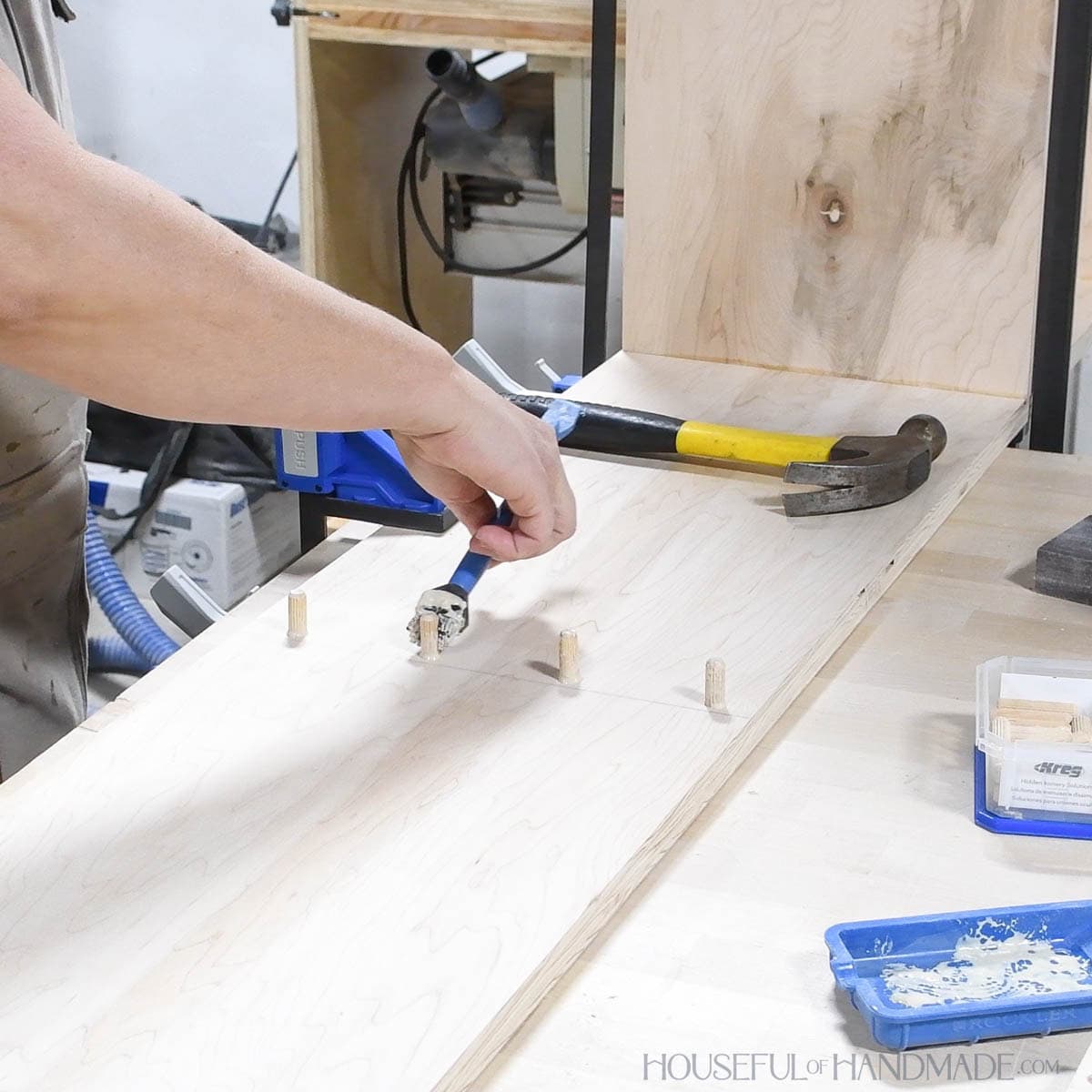 Painting glue on dowels in a board. 