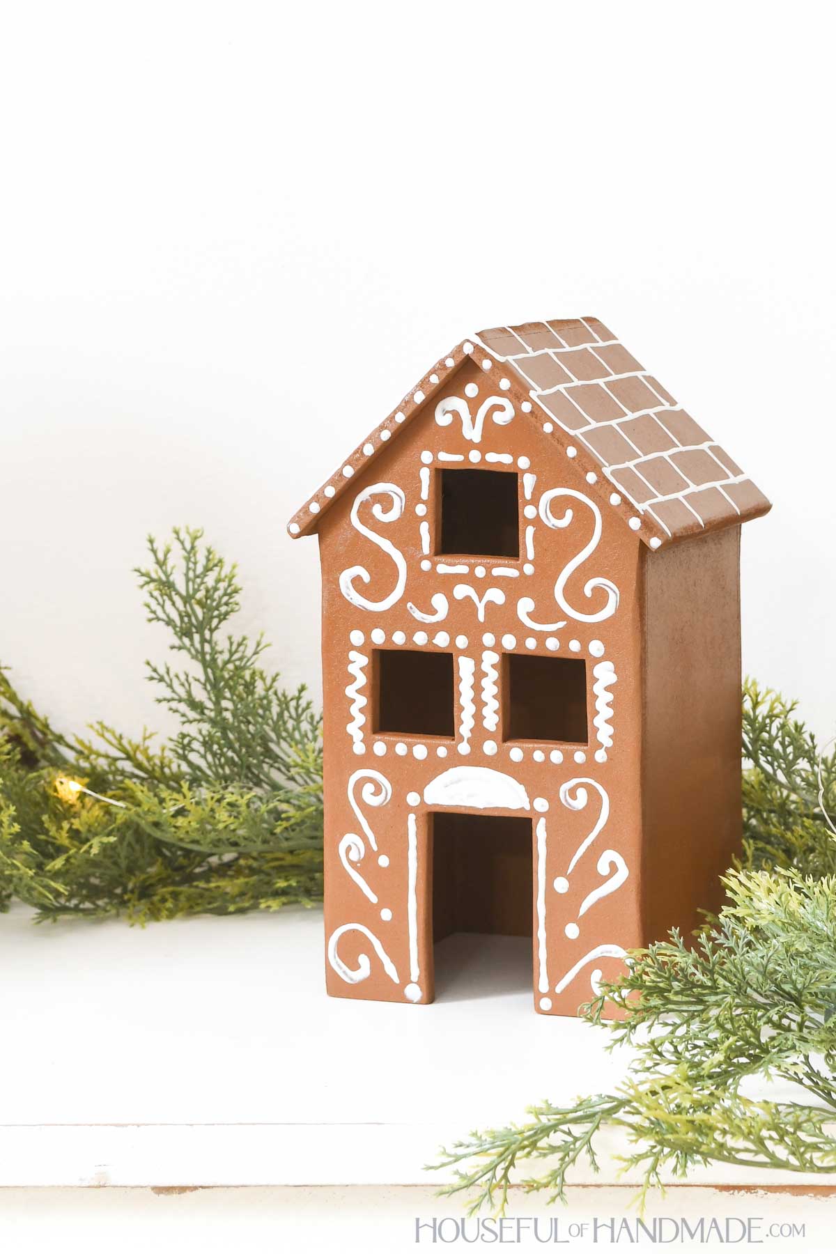 Tall wood gingerbread house decorate with puff paint to look like frosting. 
