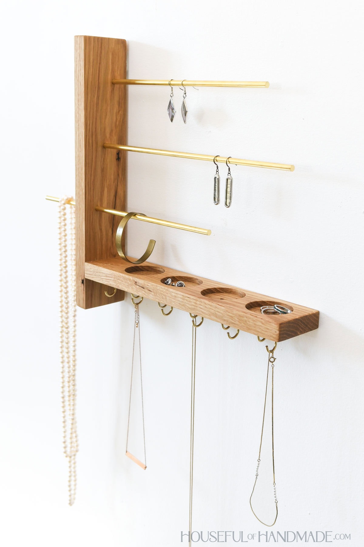 White oak wall-mounted jewelry organizer with trays for rings and studs.