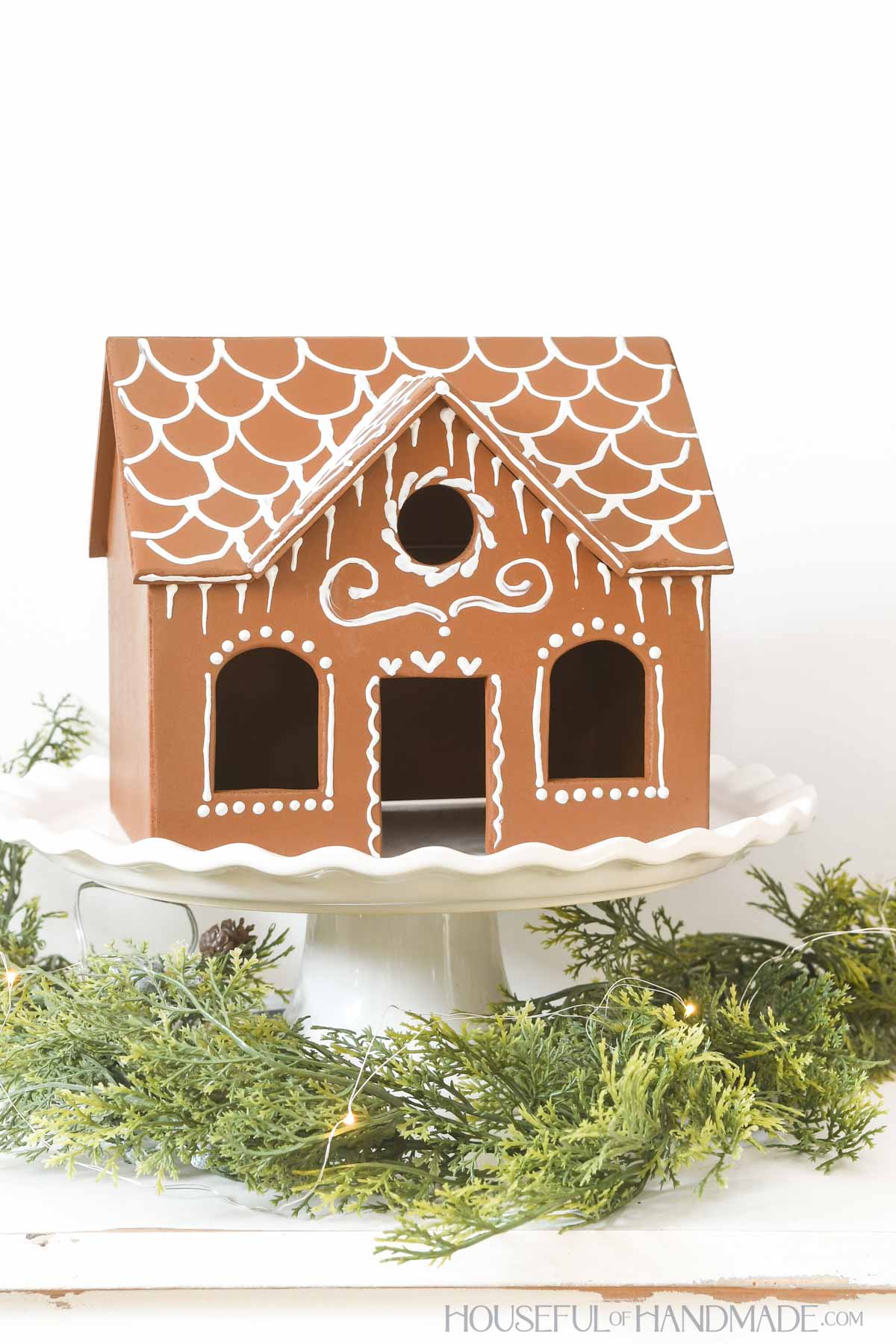 Large gingerbread house with center gable made from wood and decorated with white paint. 
