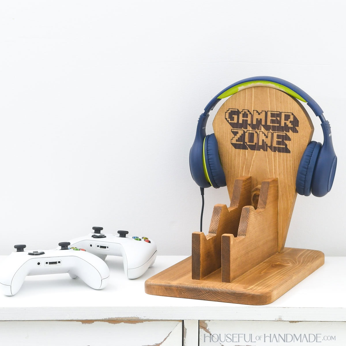 Wood stand to hold video game controllers and headphones with controllers sitting next to it.