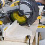 DIY acute angle jig on a Dewalt miter saw cutting a board.