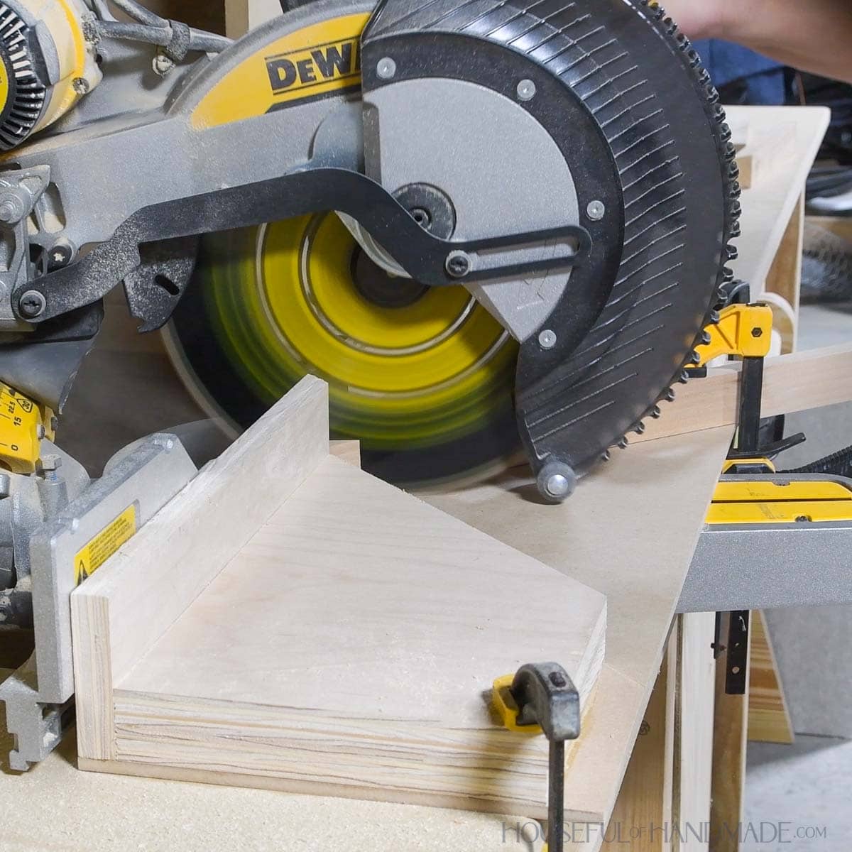 DIY acute angle jig on a Dewalt miter saw cutting a board.