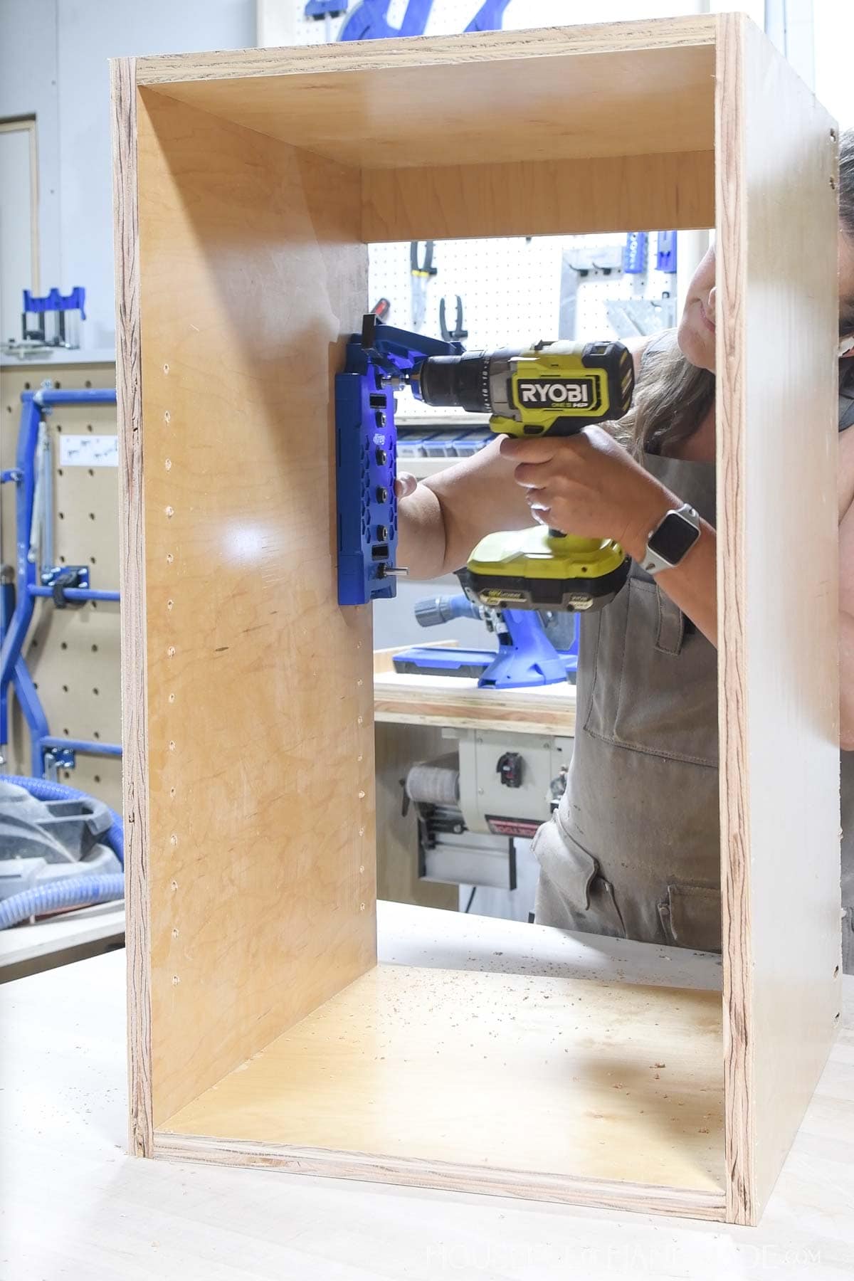 Drilling holes inside a cabinet for adjustable shelf pins using a jig.