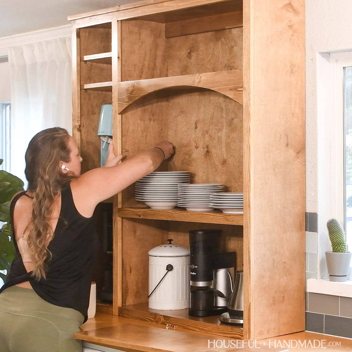 Women placing shelf pins in holes in the side of a cabinet.