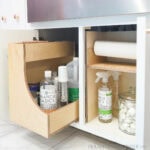 Two under sink organizers, one is a drawer and the other a shelf with paper towel holder.