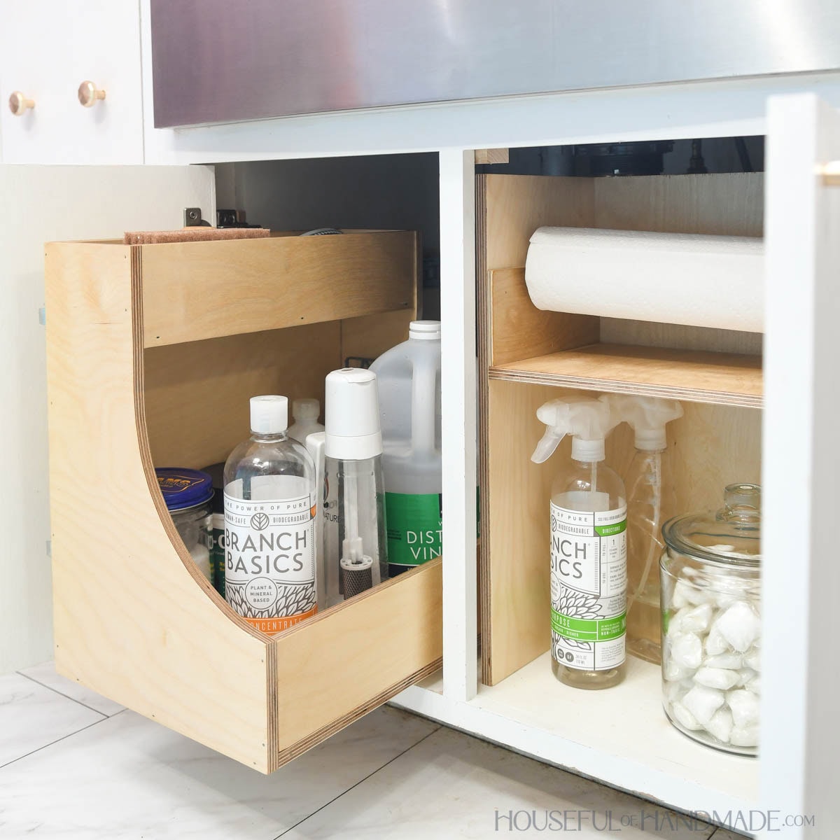 Two under sink organizers, one is a drawer and the other a shelf with paper towel holder.