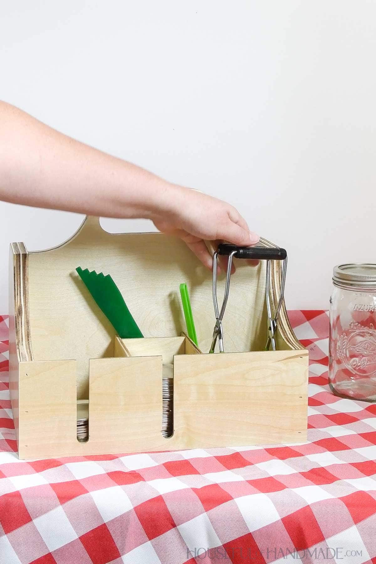 Placing a jar lifter into the front of the canning accessory caddy. 
