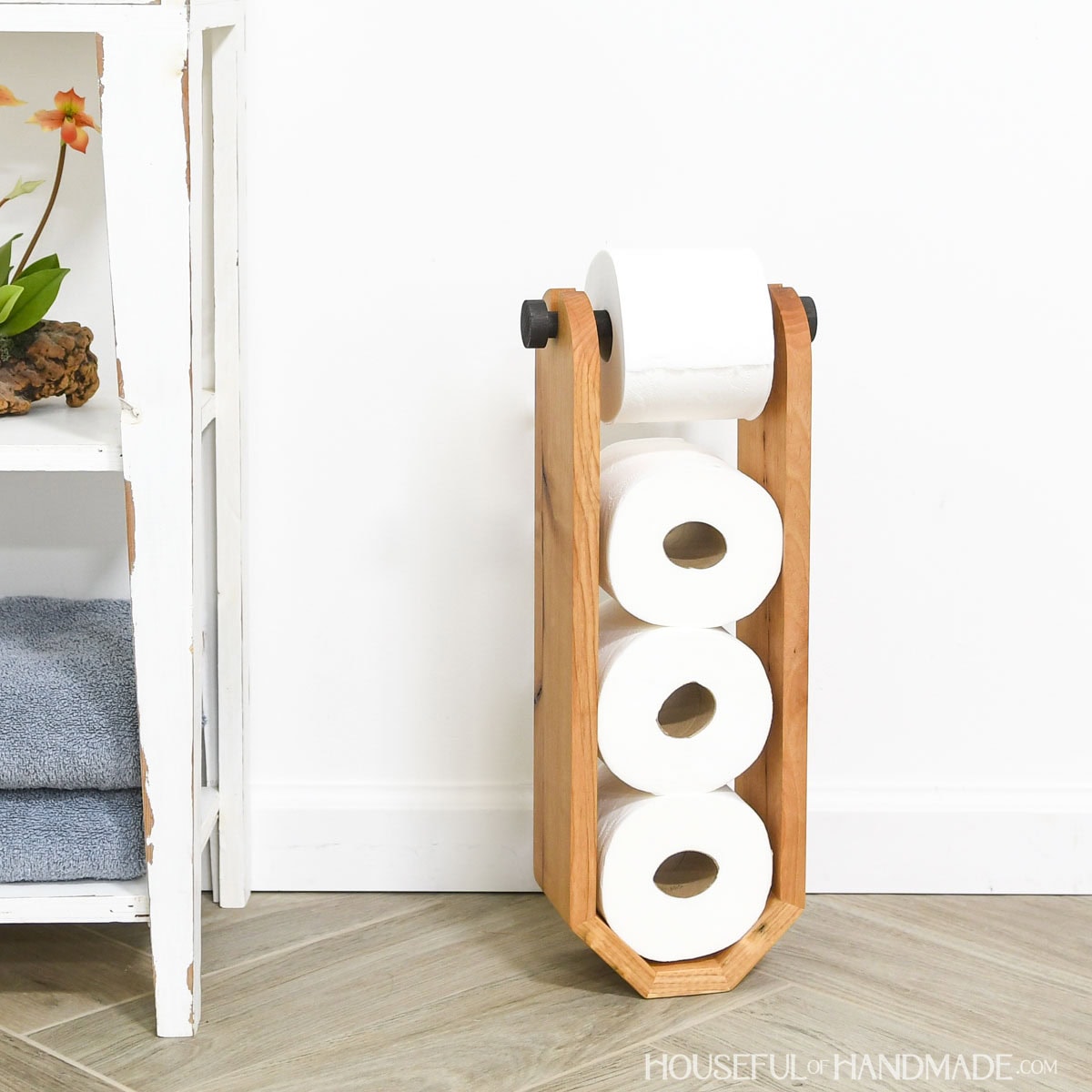 DIY freestanding toilet paper holder with storage for 3 additional toilet paper rolls.