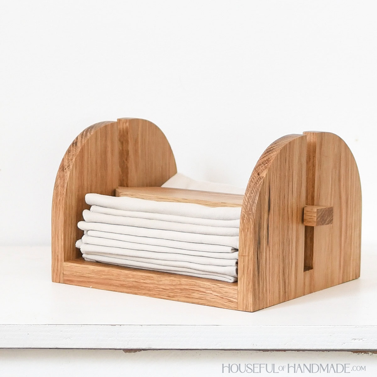 DIY napkin holder made from scrap wood with folded fabric napkins inside.