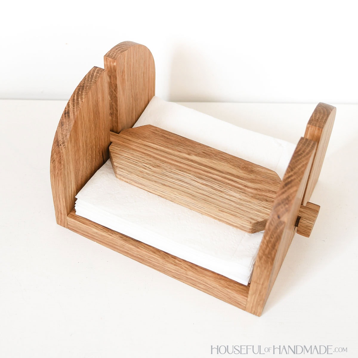 Wood napkin holder with top weight holding square paper napkins.